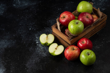 Wooden box of fresh organic apples on black background