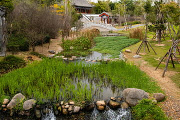 Overgroun river with stone rapids, stone bridge and hidden old chinese culture temple on background