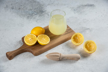 A glass cup of fresh lemon juice on a wooden board