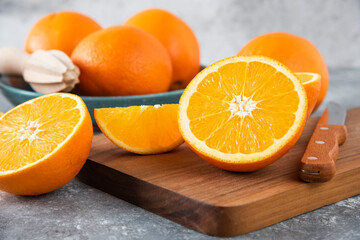Sliced orange fruits with whole oranges on a wooden board