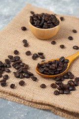 Wooden spoon full of roasted coffee beans on burlap
