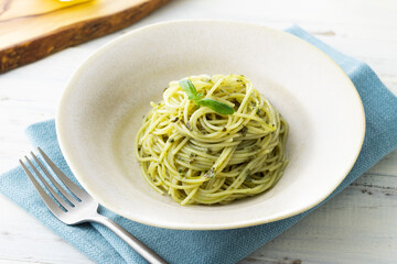 ナチュラルな背景で撮影された、バジルソースのスパゲティー