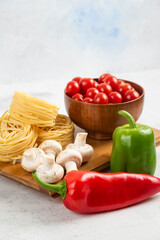 Pastas with mushrooms, chili peppers and cherry tomatoes on a wooden board