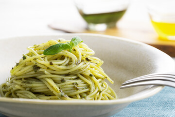 ナチュラルな背景で撮影された、バジルソースのスパゲティー