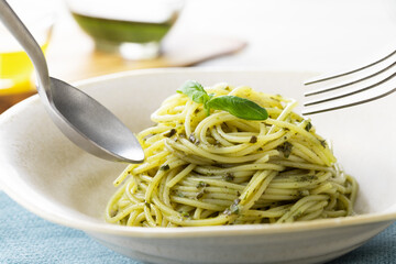 スプーンとフォークですくった、バジルソースのスパゲッティー