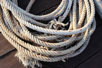 Old ship ropes pile for towing ship on wooden flooring closeup at the port.