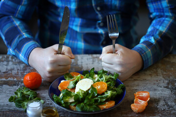 Man eating healthy salad with tangerine, mozzarella and mash salad.