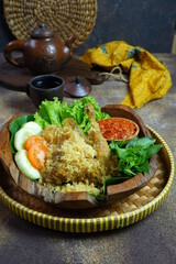 fried crispy chicken served with vegetables and sambal  in a wooden plate 