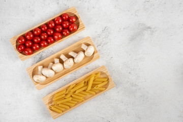 Cherry tomatoes, mushroom and pasta on a wooden board