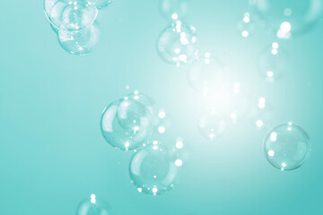 Beautiful shiny transparent soap bubbles floating on a green background.	