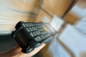Close-up, Motion blur of worker scanning bar code scanner with package boxes. Computer tools for warehouse inventory management.