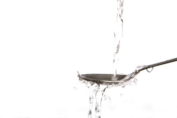 Clear water splashing onto metal spoon.