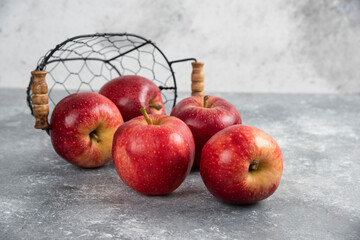 Ripe organic red apples out of metal basket on marble background