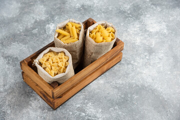 Pasta varieties in rustic basket inside a wooden tray