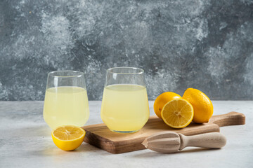 Two glass cups of fresh lemonade on a wooden board