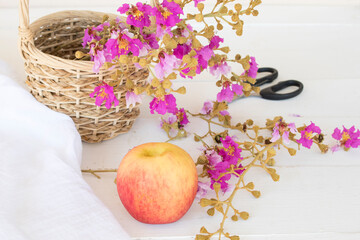 little purple flowers of asia in basket with scissors prepare florist and apple arrangement flat lay style on background white wood