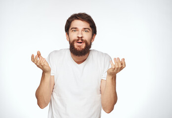 Fototapeta premium Emotional man with a beard holds his hands near his face on a light background cropped view