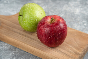 Whole wet green and red apples on wooden cutting board