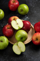 Whole and sliced green and red apples on wooden plate