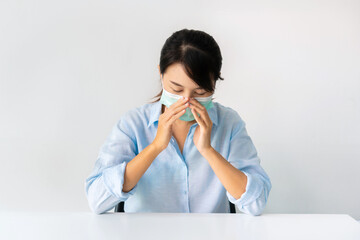 Sickness Asian girl wearing a medical face mask sitting at home over white background.