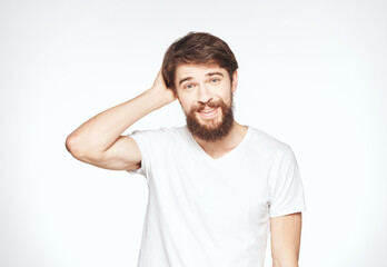 Obraz premium a man with a beard gestures with his hands on a light background Copy Space man