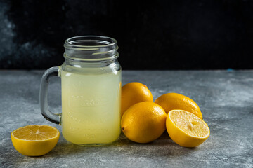 Fototapeta na wymiar A glass jar of tasty lemon juice and slices on a marble background