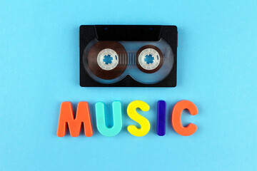 Old audio cassette and the inscription "music" on a blue background