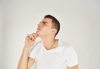 Portrait of a pensive man in a white T-shirt side view light background