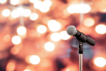 Naklejka na ściany i meble Public speaking backgrounds, Close-up the microphone on stand for speaker speech presentation stage performance with blur and bokeh light background.
