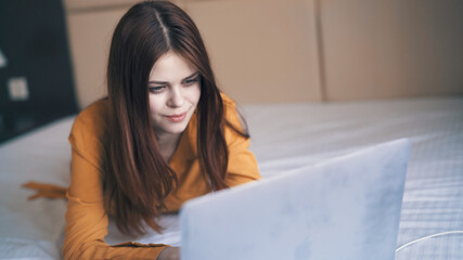 woman in the bedroom lies in bed in front of a laptop internet technology work