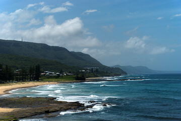 waves roll into the Wollongong coast with hill and buildings in the background