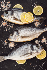 Fresh dorado fish. Dorado and ingredients for cooking at the table with black slate. Top view.