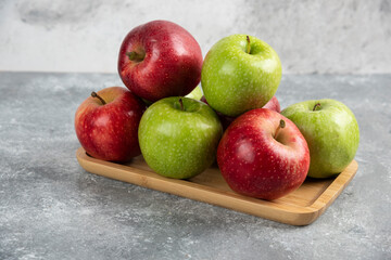 Bunch of fresh green and red apples placed on wooden plate