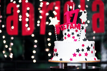 17th party or birthday party cake, sweet seventeenth white cakes with sparkle star decorative and number. dark backgrounds blurred.