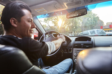 young man driving his car on a sunny afternoon, point of view from inside the car and with selective focus