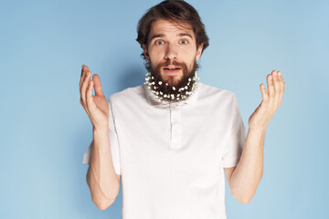 Cheerful car white T-shirt flowers in a beard close-up blue background