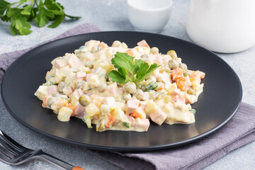 Olivier salad with mayonnaise on a plate. Russian is a traditional festive dish.