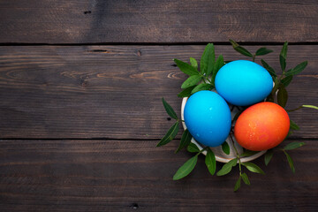 Easter eggs painted by hand colored on a dark wooden table, top view, copy space.