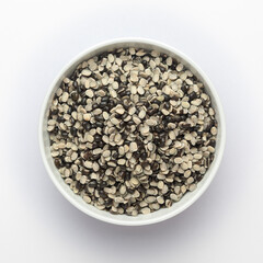 Close up of Organic split black urad dal (Vigna mungo) with shell on a ceramic white bowl. Top view 