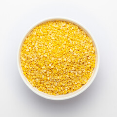 Close up of Organic yellow Gram (Vigna radiata) or split yellow moong dal on a ceramic white bowl. Top view 