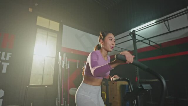 Asian young girl athlete spinning the stationary bicycle for exercise.