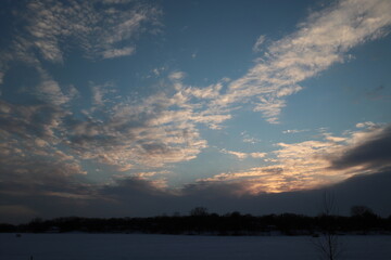 sunset in the clouds over frozen lake
