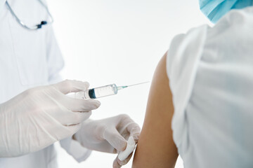 doctor in protective gloves injects a vaccine into the shoulder of a woman patient in a hospital covid 