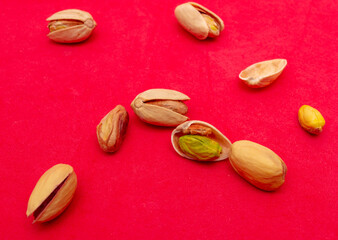 Close-up of fresh pistachio nuts on a red background.