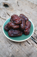 Soft focus Dates fruit in a ceramic plate closeup on wooden background