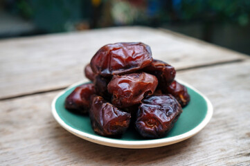 Soft focus Dates fruit in a ceramic plate closeup on wooden background