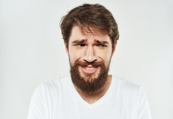 Obraz premium Bearded man in a white T-shirt on a light background sad face emotions beard