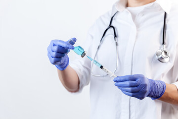 Doctor in gloves filling up syringe from bottle with vaccine, medicine
