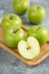 Bunch of whole and sliced green apples on wooden plate