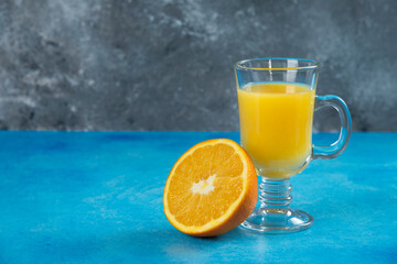 A glass cup of juice with slice of orange